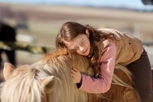 Ein Mädchen schmiegt sich an ihr Pferd