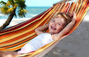 Lachendes Kind am Strand in einer Hängematte