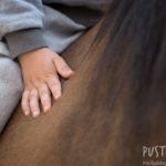Kinderhand auf dem Pferderücken