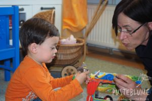 Gesine Herzog spielt mit einem kleinen Jungen mit Fingerpuppen.